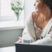 Peaceful woman in cozy sweater looking out the window with a cup of coffee, symbolizing reflection and surrender