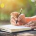 Woman writing in a notebook outdoors, symbolizing reflection, journaling, and naming your current season of business and life for personal growth and clarity.