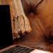 Close-up of laptop on a brown tufted couch with textured throw blanket, cozy home workspace